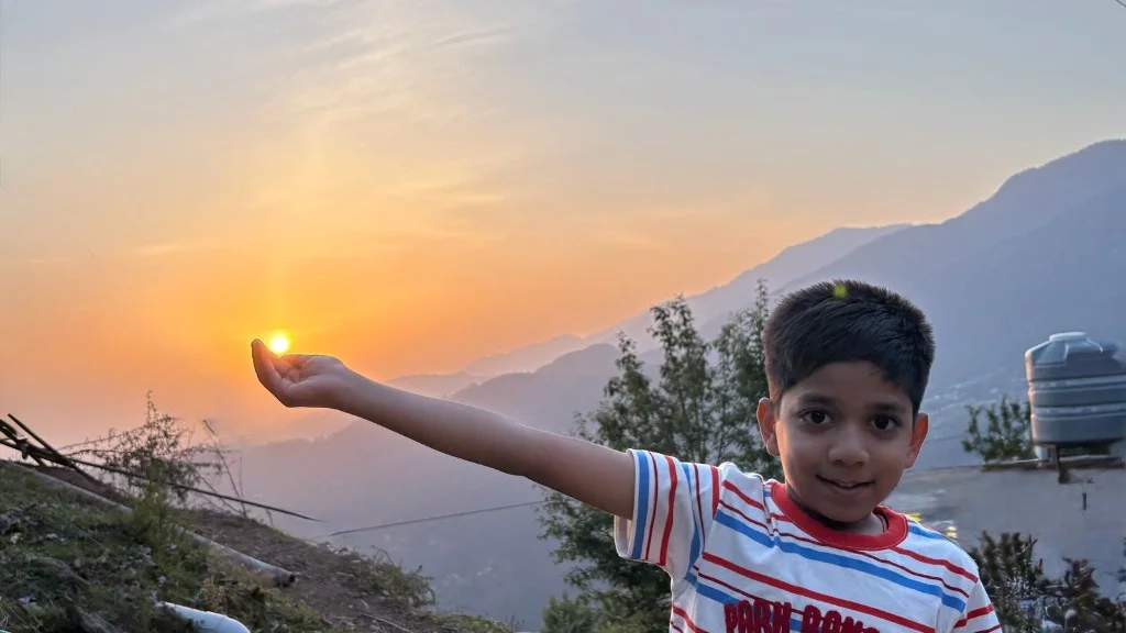 Aayaan holding the sunset sun in the mountains