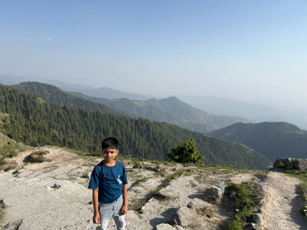 Aayaan on high mountain ridge with pine forest view